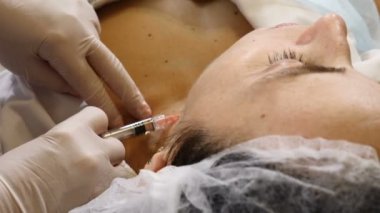 Güzellik kliniği. Eldivenli güzellik uzmanı kadın boynuna yaşlanma önleyici iğne yapıyor. Kadın güzellik yüz kozmetolojisi prosedürünü uyguluyor. Kolajen ve hiyalüronik asit enjeksiyonları. Tam Hd
