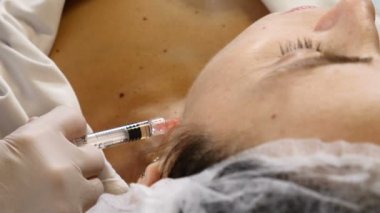 Eldivenli kozmetik uzmanı boyun kaldırma iğnesi yapıyor. Kadın müşteri sağlık kliniğinde yüz güzelliği ameliyatı oluyor. Kırışıklık önleyici kolajen ve hiyalüronik asit enjeksiyonları. Tam Hd