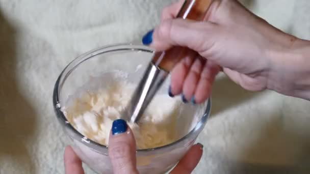 Female beautician mixes facial mask with brush. Close-up shot of cosmetologist mixing cosmetic cream in small container. Mixing ingredients for body skin care procedure. Full hd — Stock Video