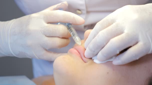 Clínica de belleza Beautician manos en guantes que hacen la inyección antienvejecimiento de la cara en labios femeninos. Mujer joven obtiene belleza procedimiento de cosmetología facial. inyecciones de colágeno. Disparo en 4k — Vídeo de stock