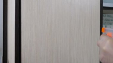 Temizlik ve sterilizasyon konsepti. Koruyucu mavi eldivenli, ıslak mendil ve spreyle mobilyaları temizleyen kadın eli. Coronavirus ev ve işyerinde önleme yayıldı. Yakın plan. 4k video