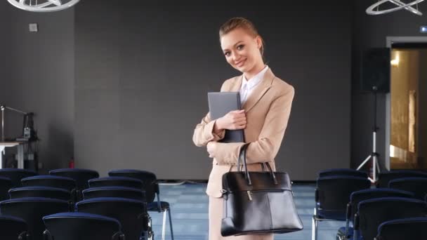 Retrato de una joven mujer de negocios caucásica atractiva y confiada en medio de una sala de conferencias vacía o en el espacio de trabajo de la oficina girando la cara y mirando a la cámara sonriendo. Posando 4 k metraje — Vídeos de Stock