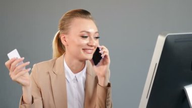 Finans, internet alışverişi ve online satın alma konsepti. Güzel genç bir kadın telefonda konuşurken çevrimiçi ödeme yapıyor ve elinde modern dizüstü bilgisayarın yanında isimsiz bir banka kartı tutarak gülümsüyor. 4 bin.