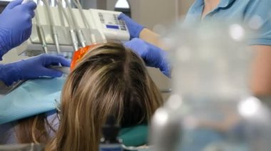 Dişçi sandalyesindeki hastayı kaldırıyorum. Modern dişçilikte diş tedavisi. Diş tedavisi prosedüründen önce kadın hastaya arka bakış. Stomatolog stomatolojide genç bir kadını tedavi etmeye hazırlanıyor. 4k video