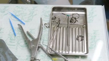 Dişçi konsepti. Diş cerrahı ameliyathanedeki metal kutudan çelik steril aletleri seçiyor ve almaya hazırlanıyor. Diş kliniğindeki tıbbi ekipmanların yakın çekimi. 4k görüntü