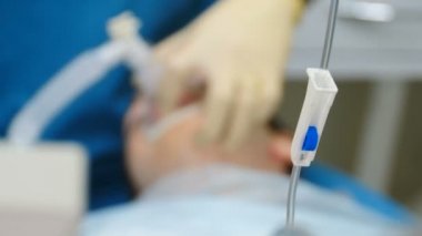 Coronavirus, COVID-19 konsepti. Tezgahı kapatın. Bulanık cerrahi operasyon arka planda perdeleniyor. Klinikte ameliyat, anestezi altında hasta, damar içi düşürücü ve odaklanmış ilaç.