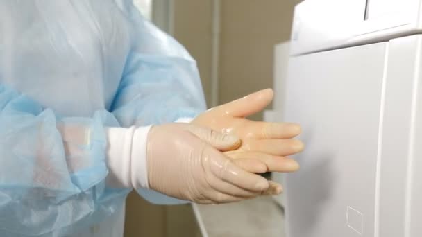 Zbliżenie ujęcia kobiety wcierającej ręce w rękawiczki z czyszczeniem antyseptycznym. Lekarz myje ręce w pobliżu zamkniętego autoklawu. Higiena, opieka zdrowotna. Kwarantanna. Koronawirus. Materiał 4 k — Wideo stockowe