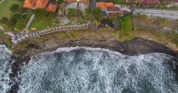 バリ島の海岸線の岩。バリ南部の海岸の崖は澄んだ紺碧の海によって洗われています。岩の上で波がクラッシュ。ドローンからの空中ビデオ撮影。4k映像 — ストック動画
