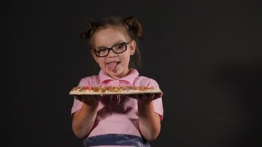 Lezzetli pizzayı hazırlayan komik bir kız. Elinde lezzetli pizzayla gülümseyen çocuk. Pizzacı reklamı. Siyah arka planda. Ağır çekim. Tam Hd