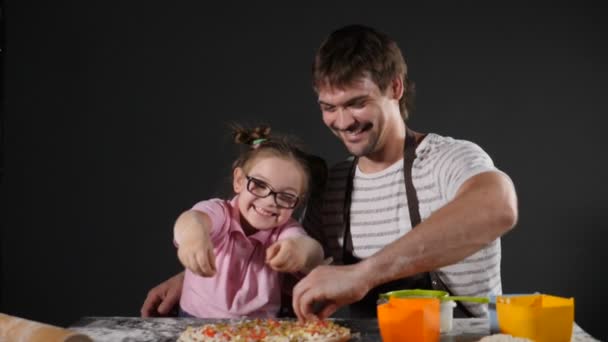 Cocinar concepto de comida hecha a mano. Chef masculino y su hija rociando ingrediente de pizza en la cocina casera. Preparando pizza italiana en el restaurante. En cámara lenta. Full hd — Vídeos de Stock