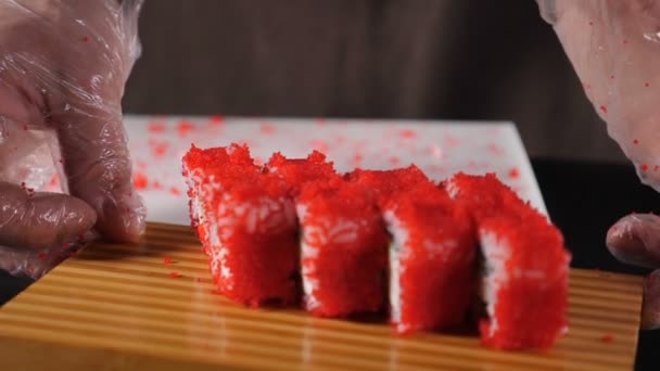 Chef präsentiert frisch gekochte Brötchen in Kaviar, serviert auf Holzbrett. Herstellung von Sushi-Rollen. Zeitlupe Food-Video. Beliebtes asiatisches Essen, Sushi im Restaurant und zum Genießen. Volle Konzentration — Stockvideo