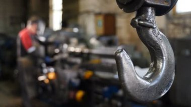 Ağır endüstri konsepti. Fabrikada çalışan vinç görüntüsü sabit. Endüstriyel fabrikada asılı metal vinç kancası. Bitki İçi bulanık ekipman ve dağınık olarak hazır hale getirilmiş ayrıntılar ile