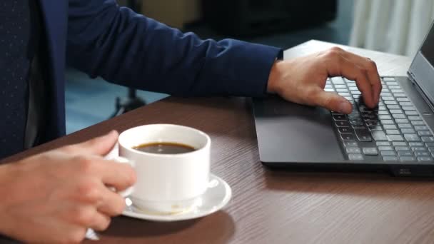 Bilgi aramak, pazarlama araştırmaları, çevrimiçi iletişim desteği ve ofis masasında iş raporu hazırlamak için dizüstü bilgisayarın klavyesine erkek eli yazarken yakın plan görüntüsü. Elle tutulan bir fincan kahve. — Stok video