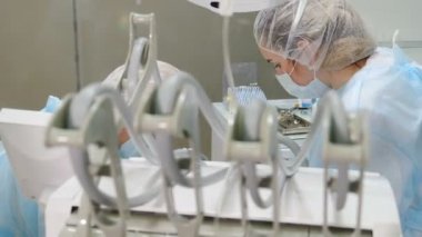 Dişçi kliniği konsepti. Diş hekimi muayenesi yapıyor. Hasta, modern dişçilikte tıbbi cerrahi ve ağız dekoltesi tedavisi görüyor. 4k video