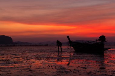 Fotoğrafçı, alacakaranlıkta uzun kuyruklu bir teknenin yanında manzara çekerken Phang Nga Körfezi Tayland 'da sular alçalırken...