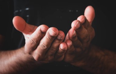 Karanlık arka planda dine ve Tanrı 'ya inançla dua eden eller. Umudun, sevginin ve bağlılığın gücü.