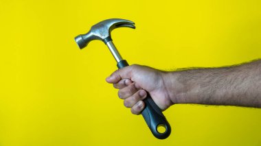 Erkek model çekiç tutuyor, sarı arka planda marangoz olarak evi tamir etmek için, İsveç