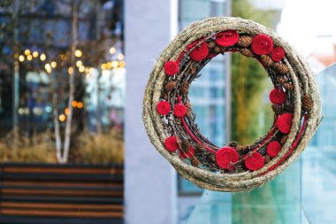 Noel dekoratif saman çelengi, dallar, çam kozalakları ve şenlikli arka planda yün ile kırmızı çiçekler. Ukrayna 'da kış günü.