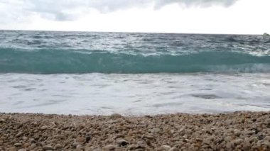Cassis Fransa 'da bulutlu bir sonbahar gününde Akdeniz' de dalgalar. Zümrüt Deniz ve küçük çakıl taşı sahili. 4k.