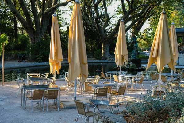 Metal masalı terk edilmiş teras ve parktaki su kenarında kapalı sarı şemsiyeler. Provence turizmi. Avignon.