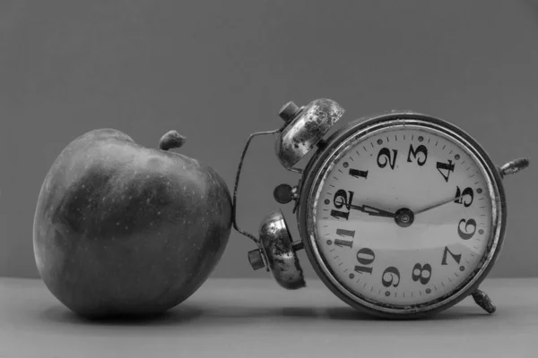 Black and white photo. Apple and inverted vintage alarm clock in Ukraine. Concept time for yourself.
