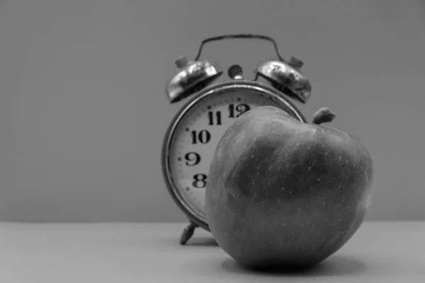 Black and white photo. Apple with vintage alarm clock in Ukraine. Concept time for yourself. Copy space.