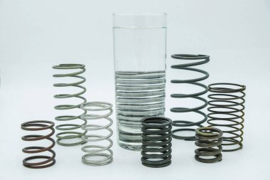 Farklı boyutlarda yaylar, farklı malzemeler ve beyaz arka planda optik bir illüzyonla dolu bir bardak suyla hayat..