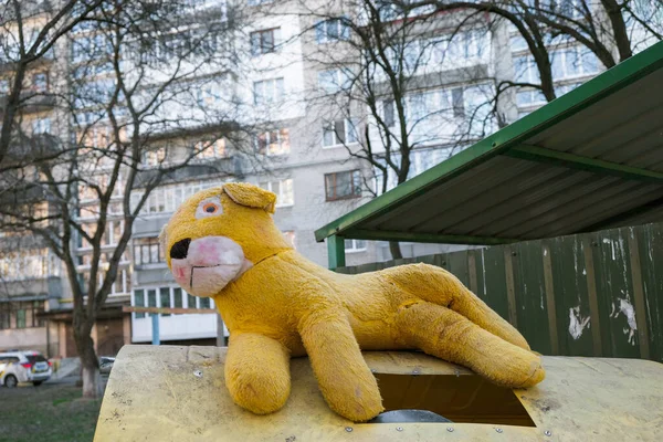 Yellow plush lion on a dump in Ukraine on the background of a multistory building.