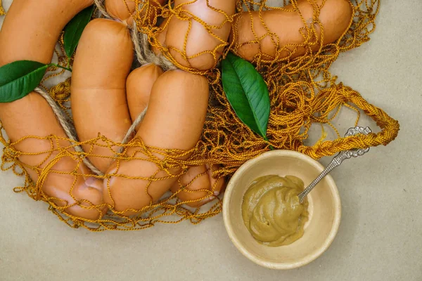 Enchidos Uma Malha Laranja Pires Com Mostarda Uma Superfície Papel — Fotografia de Stock