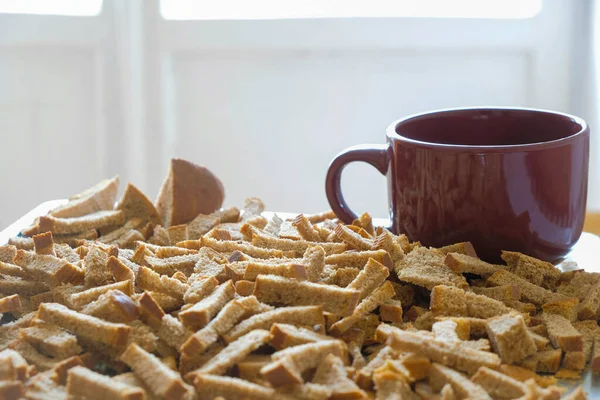 Dried bread leftovers and a cup of water on the table in the morning light.