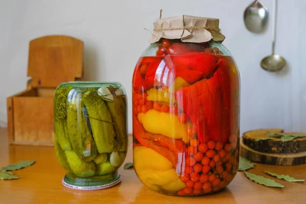 Rustic still life with pickled vegetables and an old wooden chest for salt on a white background. Appetizing pickles and paprika with red currant tomatoes.