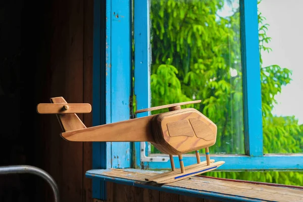 Toy wooden helicopter on the windowsill of an old wooden house in Ukraine. Flight concept.