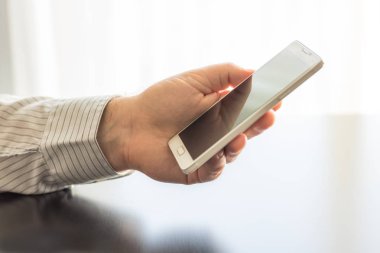 Bir adam beyaz bir cep telefonu elinde tutuyor. 