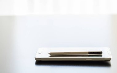 Bir koyu parlak masaüstü yüzeyinde beyaz cep telefonu