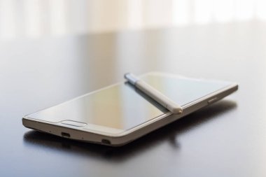Bir koyu parlak masaüstü yüzeyinde beyaz cep telefonu