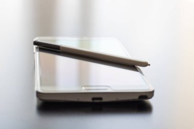 Bir koyu parlak masaüstü yüzeyinde beyaz cep telefonu