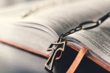 Kahverengi deri İncil açtı ve bir siyah yansıtıcı masa üstüne yerleştirilir. Rustik bir metalik çapraz İncil'den açık kitap Merkezi bağlantısını dışarı asılı duruyor. Pendent çapraz biraz masa üstü aittir. 