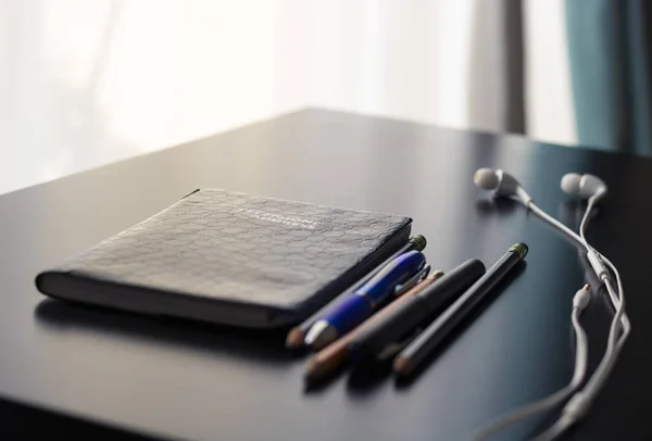 Office supplies are set on a shiny and reflective office desk. The objects on the desk signify the concept of old versus new technology. The interactive natural light and shadows create a simple yet compelling and contrasting image.