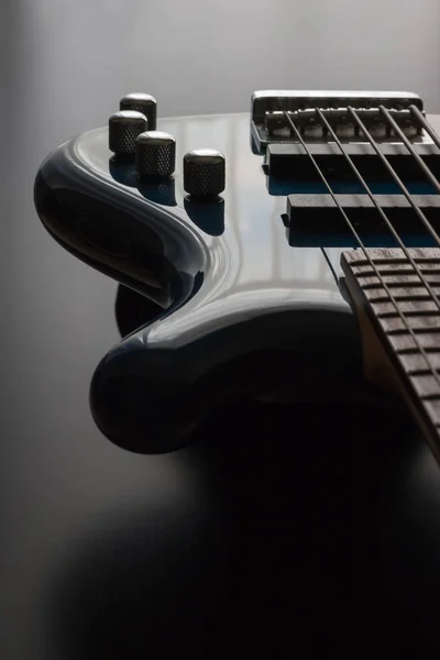 Uma guitarra azul baixo posicionado contra um fundo de madeira escura — Fotografia de Stock