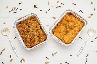 Hint yemeği, meyveli turta, subhadra ve mithai, beyaz arka planda folyo plakaları, tohumlarla serpilmiş, iki çatallı.