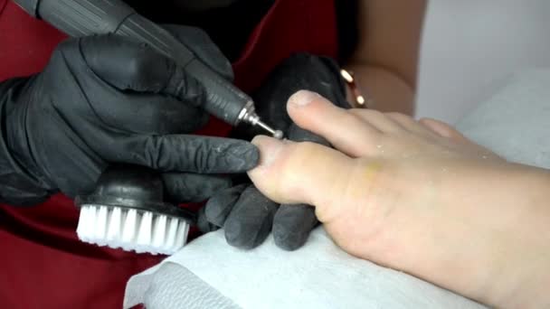 Педикюр мастер в черных перчатках работает с маршрутизатором на ногтях девочек — стоковое видео