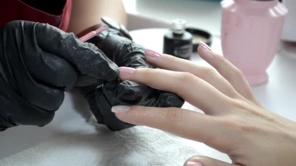 Manicure master in black gloves applies pink nail polish on nail — 비디오