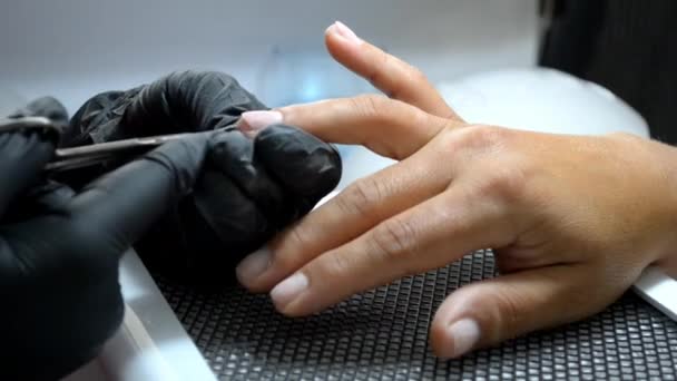 Manicure master in gloves cuts cuticle from client finger with thin scissors — Stock Video