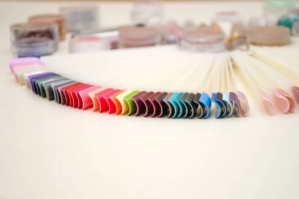 Tavolozza di disegno delle unghie di diversi colori con smalto gel su punte bianche e sfondo, vasi con scintille e decorazioni — Foto Stock