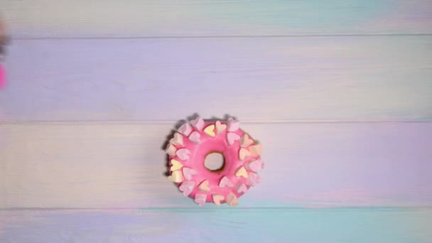 Weibliche Hand verteilt Word Donut in Buchstaben über rosa Donut auf Regenbogenhintergrund — Stockvideo