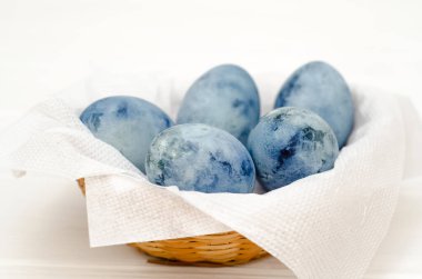 Beş mavi mermer yumurta, sepetteki ejderha yumurtasına benzer, amber çayına boyanmış, beyaz arka planda, kopyalanmış bir kart için.