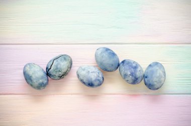 Altı mavi mermer yumurta, biri çatallı, amber çayıyla boyanmış, gökkuşağı arka planında yatıyor.