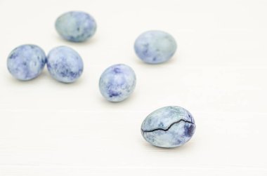 Ejderha yumurtasına benzeyen altı mavi mermer yumurta, biri çatallı, amber çayıyla boyanmış, beyaz arka planda, kopyalanmış bir kart için.