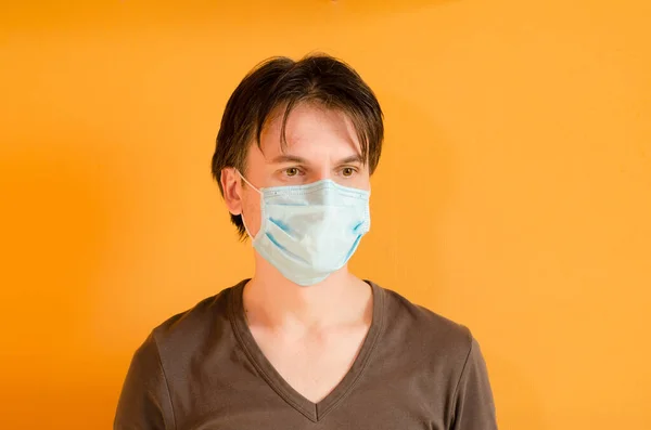Muž s maskou, který ho chrání před virem. Koncept epidemie koronaviru. Unavený muž s lékařskou modrou maskou — Stock fotografie