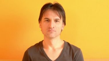 Avrupalı adam çok geniş esniyor, sarı arka planda ağzını kapatmıyor.